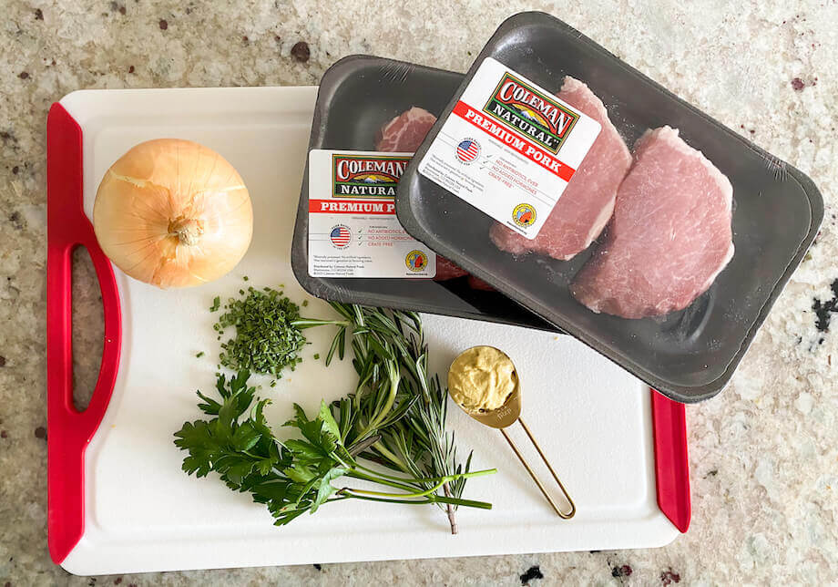 Uncooked pork chops on a cutting board with other ingredients