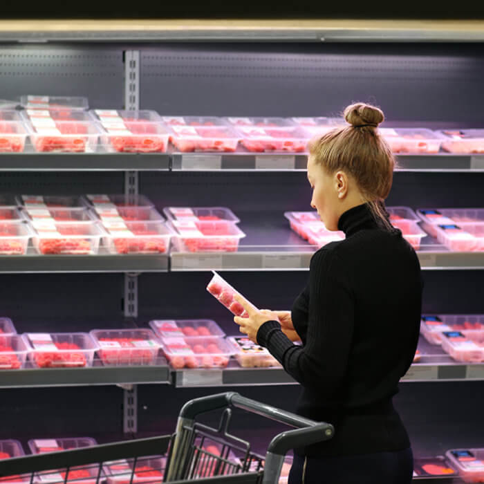 woman looking at packaging for meat