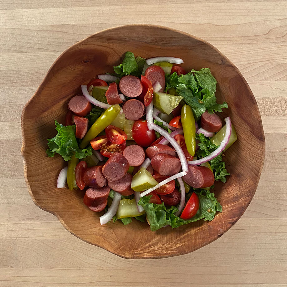 hot dog chicago dog salad in a wooden bowl