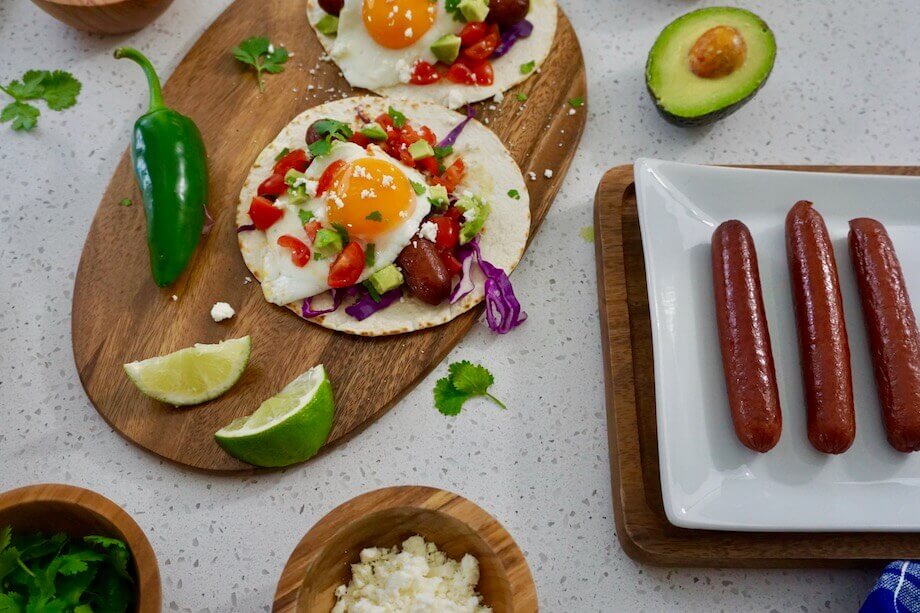 Tacos with avocado, eggs, peppers, and hot dogs with slices of lime
