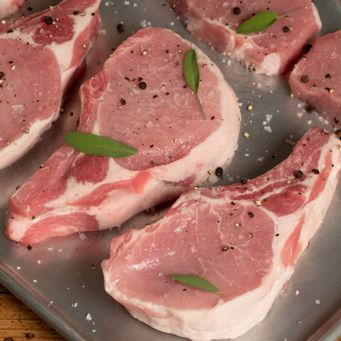seasoned raw pork chops on metal