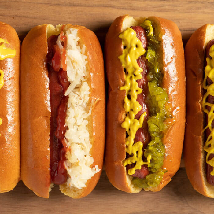 four hot dogs dressed and lined up