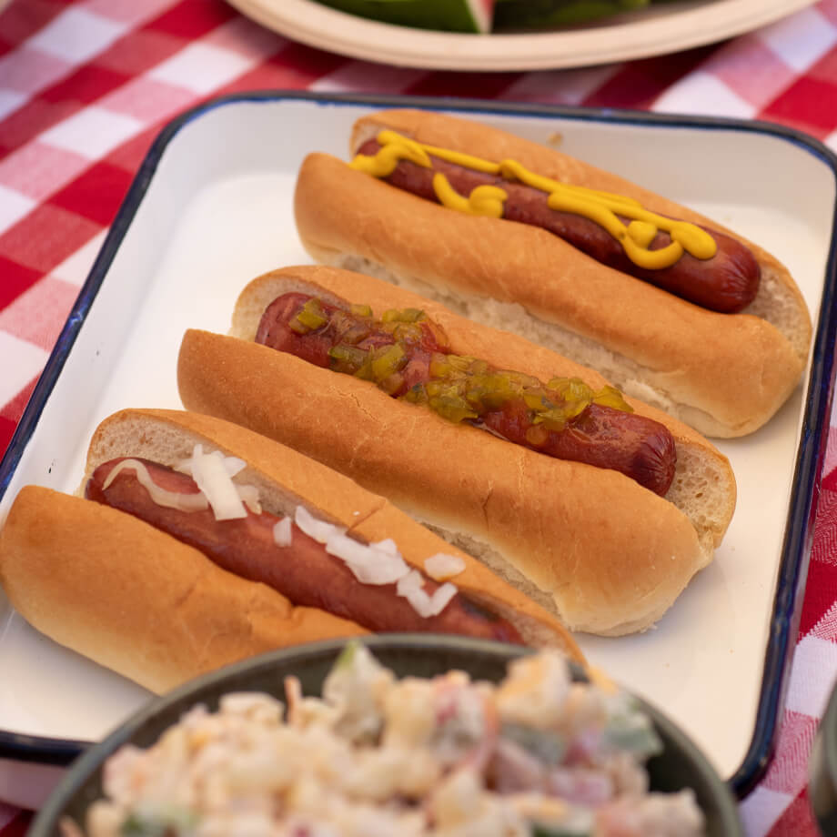 three hot dogs on tray on picnic table