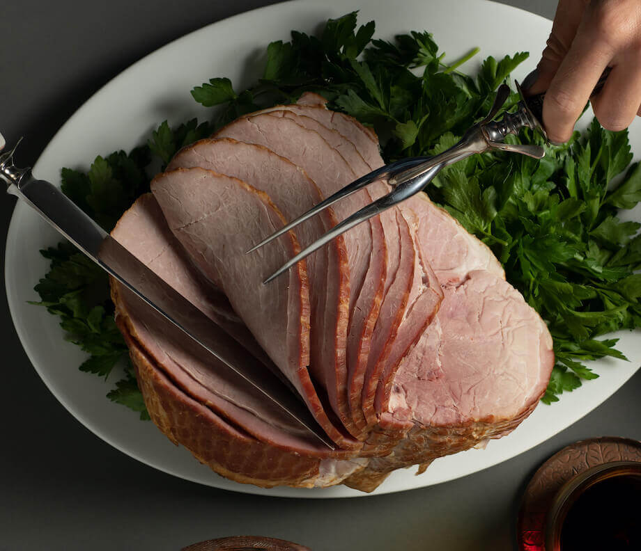 Ham being sliced on a white plate