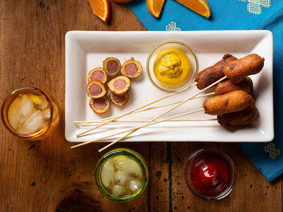 Mini corn dogs on a stick with mustard and ketchup