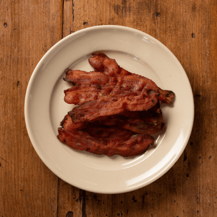 A plate of cooked bacon on a wood table