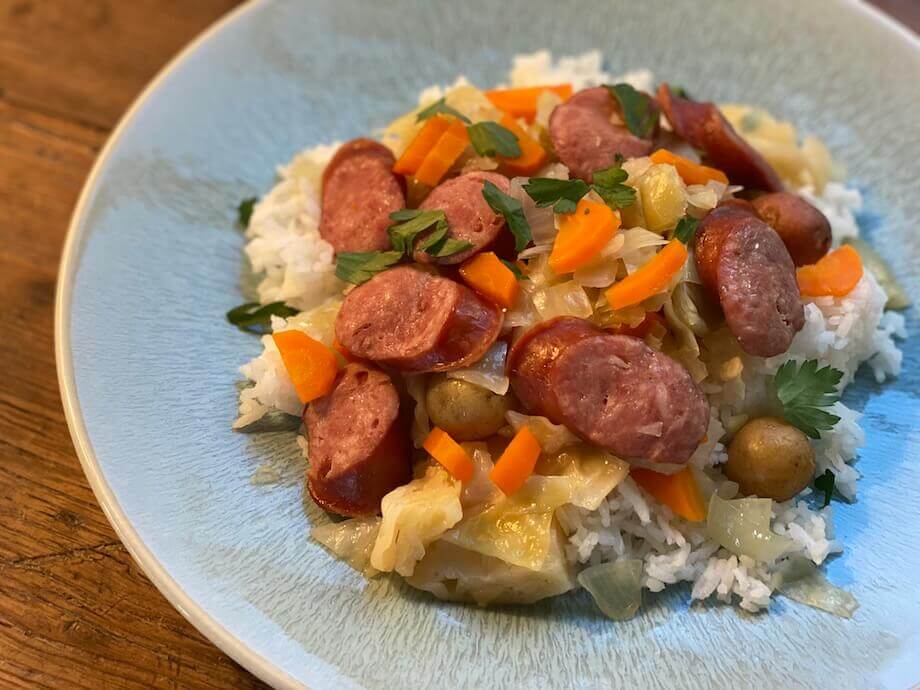 Slow cooked polish sausage and cabbage with rice on a blue plate
