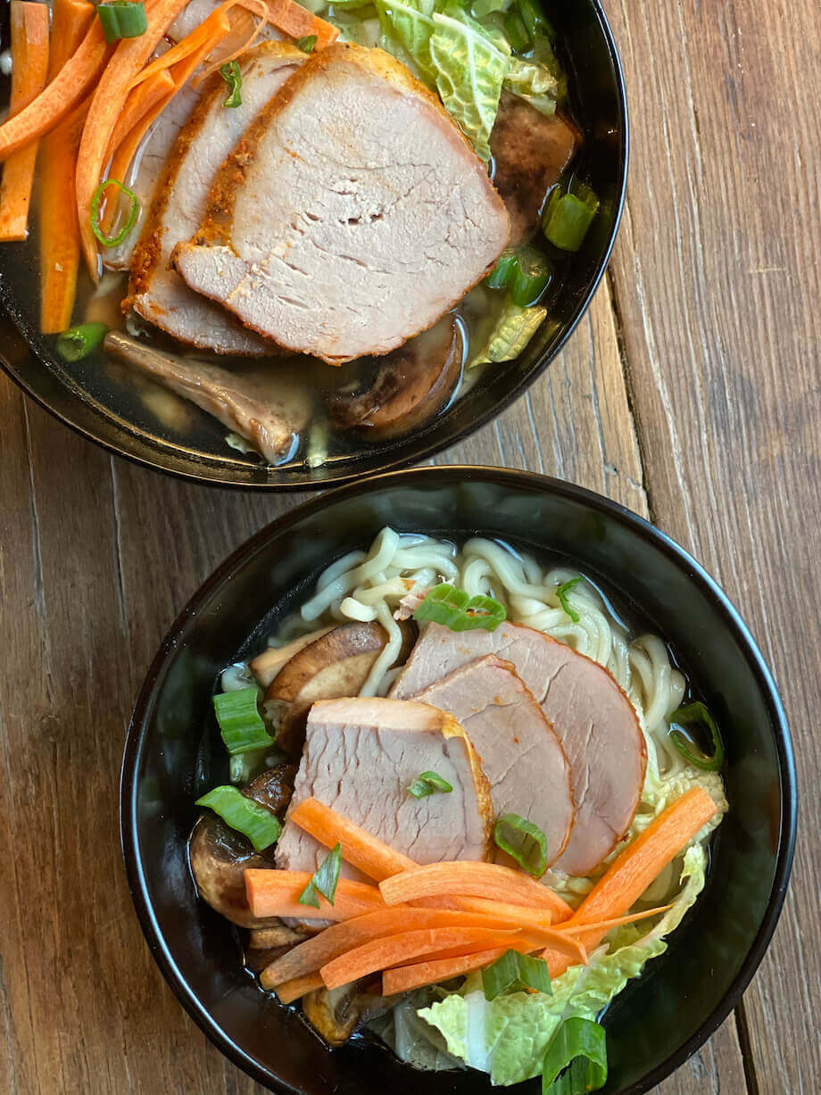 Pork loin in a bowl with ramen noodles and vegetables
