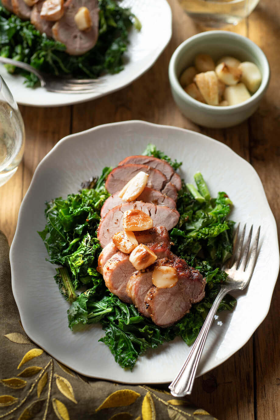 Pork on a bed of kale on a white plate