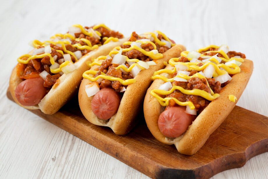 Three Coney Dogs on a wooden cutting board