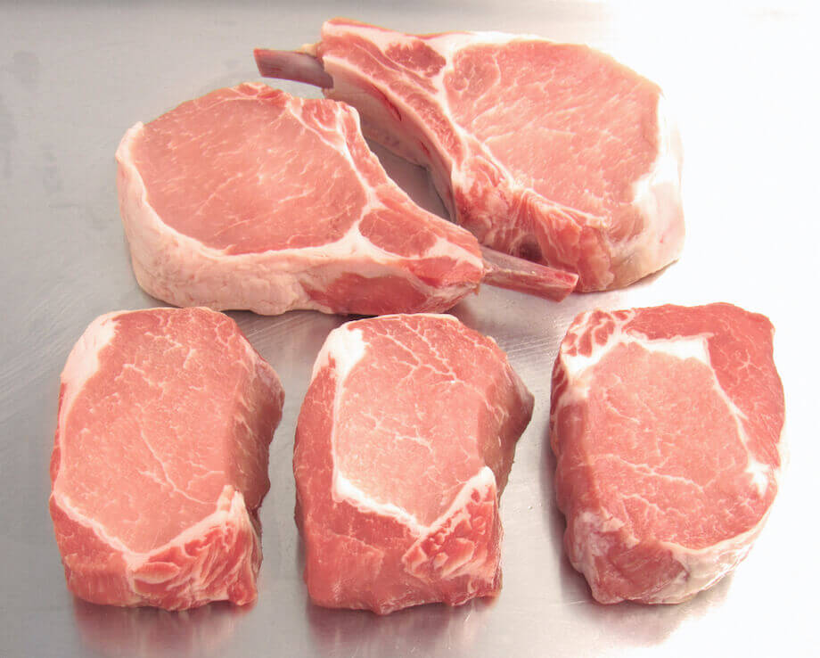 Raw pork chops sitting on a counter
